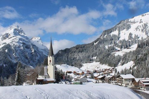 Sunny skies above the traditional buildings and church in Schröcken, Austria – Weather to ski – Who got the most snow in the Alps in 2025-26?