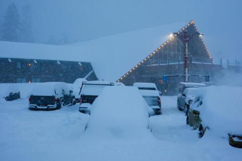 Cars buried under deep snow outside a lodge in Mammoth, California, during heavy snowfall on 2 February 2024