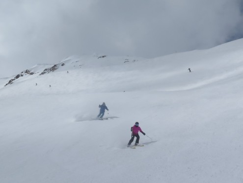 Skiers descending a wide, snow-covered slope at Snowbird, Utah, on 11 March 2024, with one skier kicking up powder snow